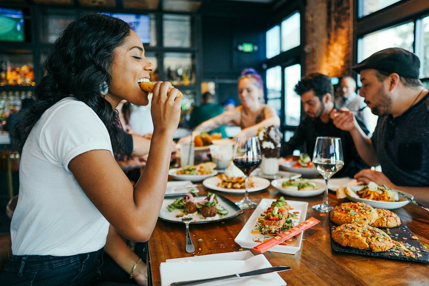Przyjaciele dzielą się jedzeniem i piciem przy stoliku w restauracji.