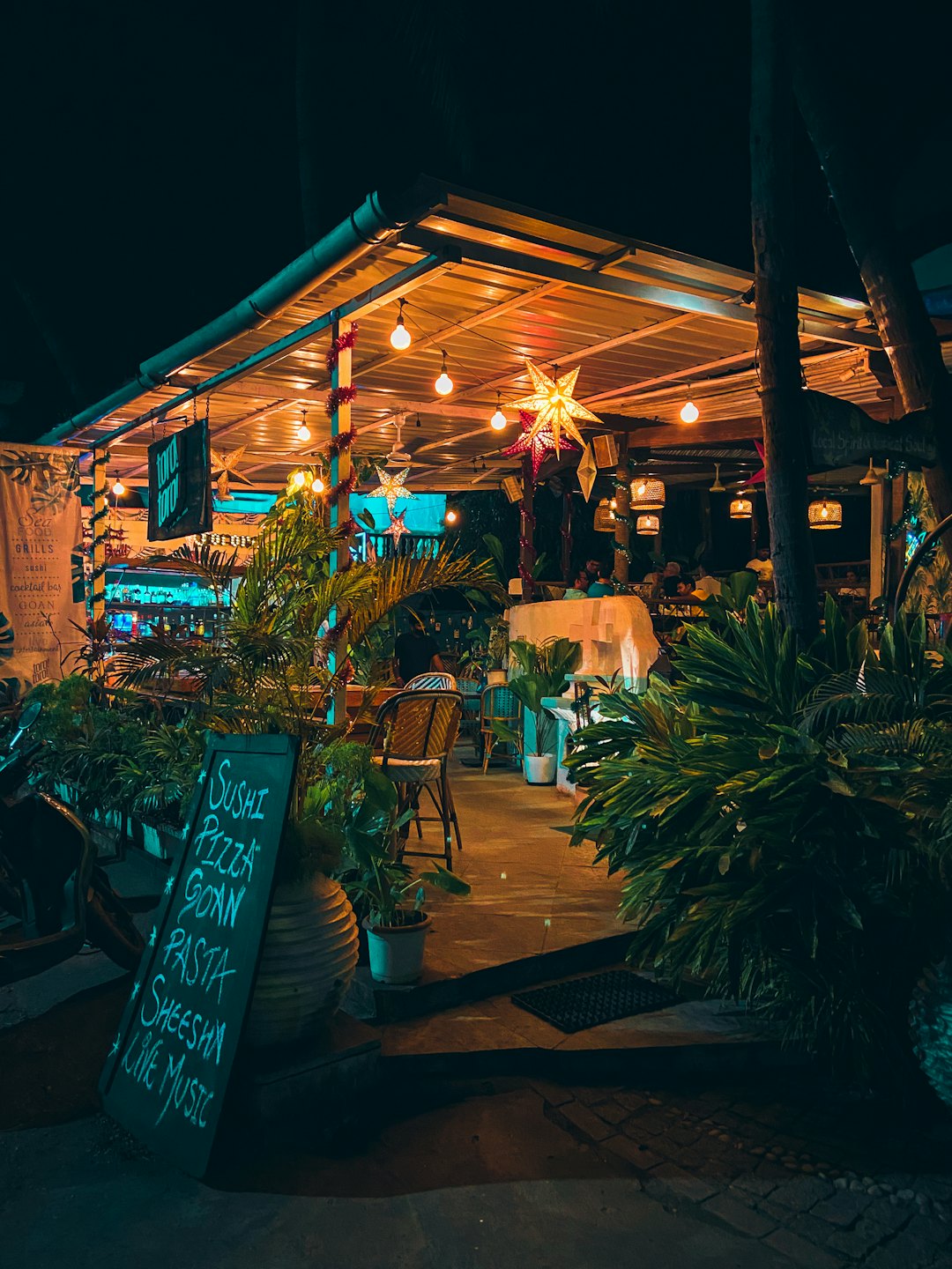 Wieczorem restauracyjny ogródek z lampkami i roślinami.